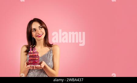 Eine lächelnde Frau mit braunen Haaren und rotem Lippenstift, die ein glitzerndes silbernes Kleid trägt Stockfoto