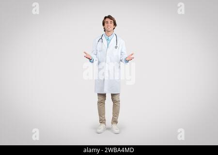 Fröhlicher Arzt mit offenen Händen in Willkommensgeste Stockfoto