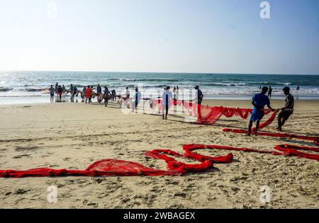 Fischer am Strand von Benaulim im indischen Goa ziehen ihre Netze an Land und sortieren den Fang Stockfoto