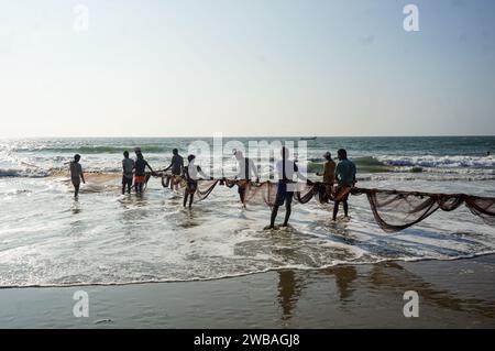 Fischer am Strand von Benaulim im indischen Goa ziehen ihre Netze an Land und sortieren den Fang Stockfoto