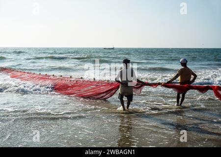 Fischer am Strand von Benaulim im indischen Goa ziehen ihre Netze an Land und sortieren den Fang Stockfoto