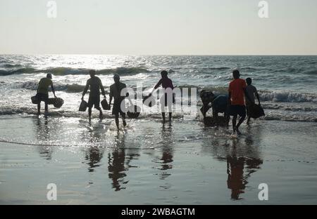 Fischer am Strand von Benaulim im indischen Goa ziehen ihre Netze an Land und sortieren den Fang Stockfoto