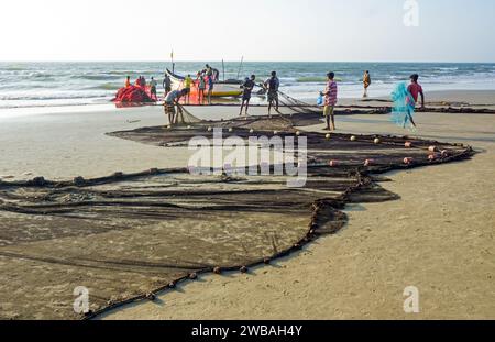 Fischer am Strand von Benaulim im indischen Goa ziehen ihre Netze an Land und sortieren den Fang Stockfoto