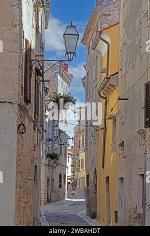 Bild einer typischen Straßenszene aus der historischen kroatischen Stadt Voznjan mit Kopfsteinpflasterstraßen und alten Gebäuden im Morgenlicht Stockfoto
