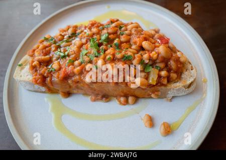 Hausgemachte Bohnen auf Toast in Tomaten und Gemüsesauce auf Sauerteig Toast mit Olivenöl Stockfoto