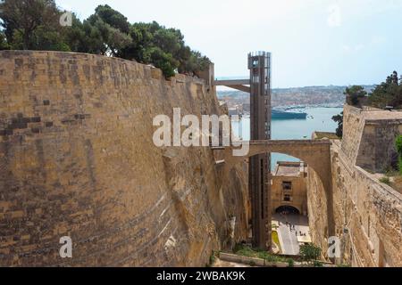 Blick auf den Barrakka Lift, Valletta, Malta, der sich im Graben der Befestigungsanlagen von Valletta befindet und Lascaris Wharf mit St. verbindet Peter und Paul Stockfoto