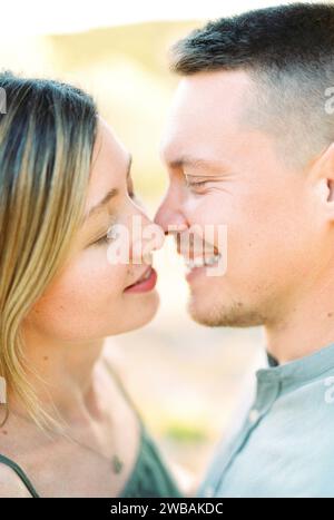 Die junge Frau küsst fast einen lächelnden Mann. Hochformat Stockfoto