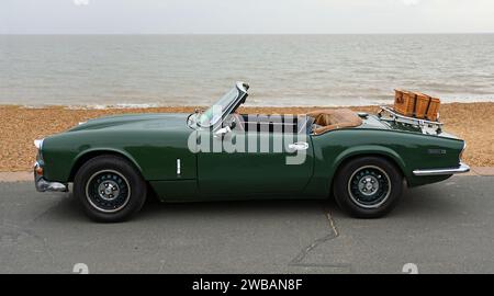 Klassischer Green Spitfire Mk 4-Wagen mit Picknickkorb auf Schuh, der am Strand der Promenade und am Meer im Hintergrund geparkt ist. Stockfoto