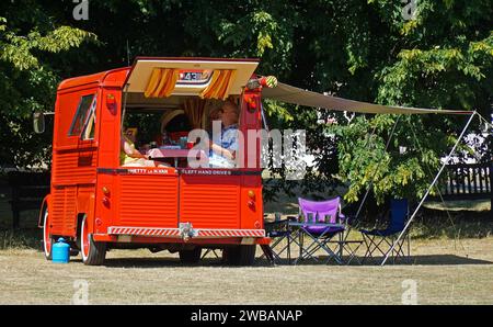 Paare beim Picknick im restaurierten, klassischen Citroën-Minibus Typ H an sonnigem Tag. Stockfoto