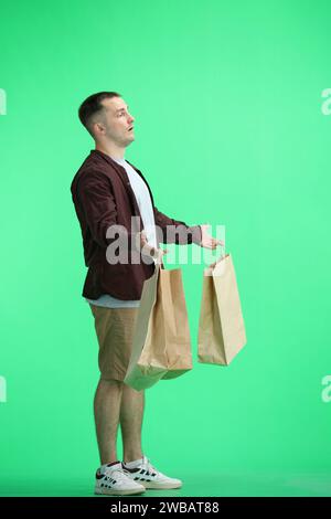 Ein Mann in einem braunen Hemd, auf grünem Hintergrund, in voller Länge, mit Taschen Stockfoto