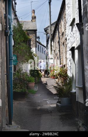 Zurück von zwei Männern, die eine hübsche enge Straße in Mousehole, einem malerischen Fischerdorf an der Südküste von Cornwall, entlang gehen Stockfoto