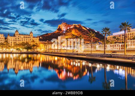 Beleuchtetes Panorama der Altstadt von Alicante in der Abenddämmerung mit Schloss Santa Barbara und Hafen, Spanien Stockfoto