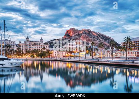 Beleuchtetes Panorama der Altstadt von Alicante in der Abenddämmerung mit Schloss Santa Barbara und Hafen, Spanien Stockfoto