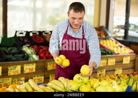 Mann Verkäufer, der im Supermarkt arbeitet und Äpfel auf der Theke verteilt Stockfoto