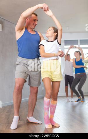 Glücklicher Vater und glückliche Tochter, die zusammen mit anderen Familienmitgliedern in Paaren tanzen Stockfoto