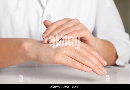 Dermatologe testet kosmetisches Produkt am weißen Tisch, Nahaufnahme Stockfoto