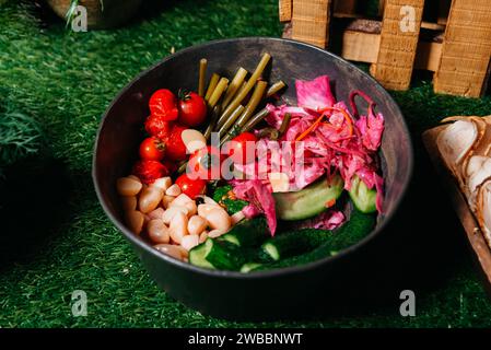 Eine appetitliche Auswahl an eingelegtem Gemüse einschließlich Sauerkraut, Rampen, Knoblauch, Kirschtomaten und leicht eingelegten Gurken in einer dunklen Schüssel auf einem Stockfoto
