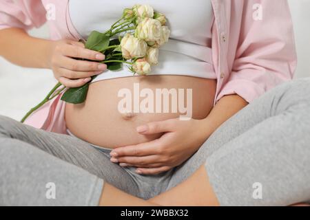 Schwangere Frau in rosa Hemd mit Rosen, Nahaufnahme Stockfoto