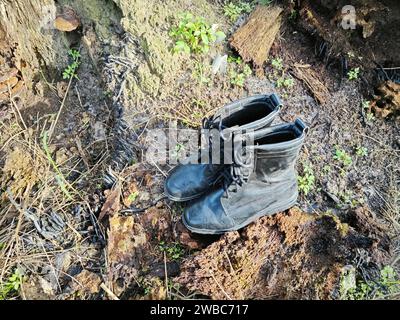Alte, weggeworfene Lederstiefel, die auf der wilden Wiese gefunden wurden. Stockfoto