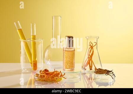 Eine Serumflasche ohne Marke auf gelbem Hintergrund mit einigen Laborgeräten, die Cordyceps und Essence enthalten. Platz für Design-Verpackungen. Vorn VI Stockfoto