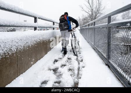 Chicago, USA. 9. Januar 2024. Chicago Wetter : Ein Radfahrer spaziert mit seinem Fahrrad, während in den westlichen Vororten Chicagos starker Schnee fällt. Am Ende der Woche wird noch mehr Schnee erwartet, bevor die Temperaturen von -14 °C und darunter deutlich kälter werden. Quelle: Stephen Chung / Alamy Live News Stockfoto