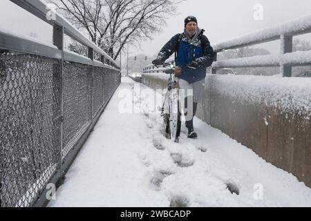 Chicago, USA. 9. Januar 2024. Chicago Wetter : Ein Radfahrer spaziert mit seinem Fahrrad, während in den westlichen Vororten Chicagos starker Schnee fällt. Am Ende der Woche wird noch mehr Schnee erwartet, bevor die Temperaturen von -14 °C und darunter deutlich kälter werden. Quelle: Stephen Chung / Alamy Live News Stockfoto