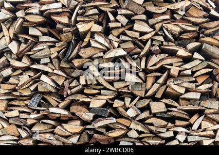 Holzhaufen liegt in einem Haufen, gehackt zum Verbrennen im Ofen. Fein gehacktes und stapeltes Brennholz, Hintergrund. Trockenes Brennholz, Textur, Hintergrund. Feuer Stockfoto