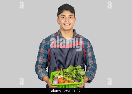 Junger männlicher asiatischer muskulöser Farmer zeigt verschiedene Gesten und Ausdrücke zusammen mit der Gemüseernte Stockfoto