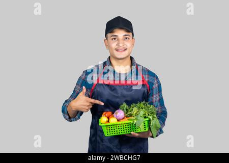 Junger männlicher asiatischer muskulöser Farmer zeigt verschiedene Gesten und Ausdrücke zusammen mit der Gemüseernte Stockfoto