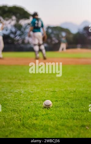 Baseballball sitzt auf dem Diamantfeld. Fänger und Pitcher im unscharfen Hintergrund. Stockfoto