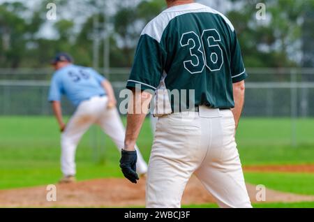 Baseballspiel, Läufer auf der ersten Basis beobachtet den Pitcher und macht sich bereit, die zweite Basis zu stehlen. Stockfoto