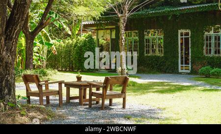 Zwei bemalte Stühle im Freien auf einem üppigen Garten. Holzstuhl und Tisch im Garten. Ein Ort zum Entspannen und Entspannen im Sommergarten. Stockfoto