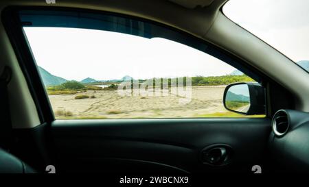Blick in das Seitenfenster eines Autos während der Fahrt auf der Landstraße. SideView-Fahrzeugspiegel des Beifahrers. Reise und Reise. Stockfoto