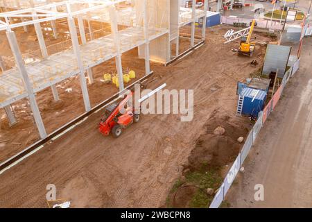 Drohnenfotografie der Baustelle eines großen Geschäftsgebäudes mit Baumaschinen und Bauarbeitern am sonnigen Herbstmorgen Stockfoto