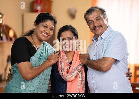 Glückliche lächelnde Mittelklasseltern mit Tochter, die zu Hause Kamera schaut - Konzept von Familienbindung, Beziehung und Generationen Stockfoto