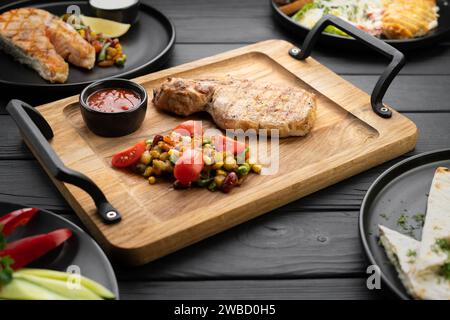 Gegrillte Steaks, Fisch, Filet und Rippchen werden auf einem Holztisch in einem Restaurant serviert Stockfoto