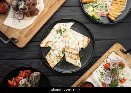 Georgianische Küche auf dem Grill gebratene Gerichte, Kebabs und Pita-Brot mit Käse, serviert auf Tellern auf einem Holztisch in einem Restaurant Stockfoto