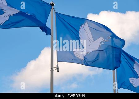 Drei blaue Friedensfahnen hintereinander, bedruckt mit einer Taube mit einem Olivenzweig im Schnabel. Die Taube mit der Branche ist das internationale Symbol des Friedens. Stockfoto