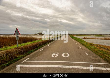 Werkendam, Niederlande, 29. Dezember 2024: Asphaltstraße zwischen dem Fluss und den überfluteten Rückhaltezonen als Teil des Flussprojekts Stockfoto