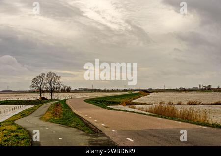 Werkendam, Niederlande, 29. Dezember 2024: Mäandernde Straße zwischen Gewässern im Rahmen des Projekts Room for the River in der Region Noordwaard Stockfoto