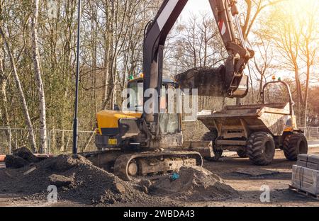 Bagger, der halbtrockene Betonmischung auf der Baustelle in den Kipper lädt Stockfoto