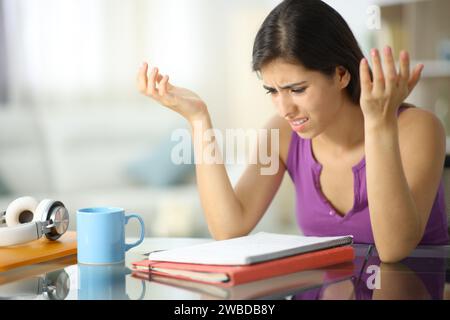 Frustrierter Student, der sich zu Hause über Notizen beschwert Stockfoto