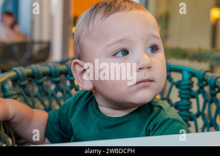 Porträt netter Junge, der draußen auf einem Stuhl sitzt. Stockfoto