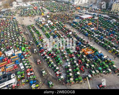 Augsburg, Deutschland. Januar 2024. Bauern mit Hunderten von Traktoren nehmen an einer Rallye am Plärrer in der Stadt Teil (Fotos mit einer Drohne). Als Reaktion auf die Sparpläne der Bundesregierung hat der Bauernverband eine Woche lang mit Kundgebungen gefordert. Am 15. Januar wird es in einer großen Demonstration in der Hauptstadt enden. Quelle: Peter Kneffel/dpa/Alamy Live News Stockfoto