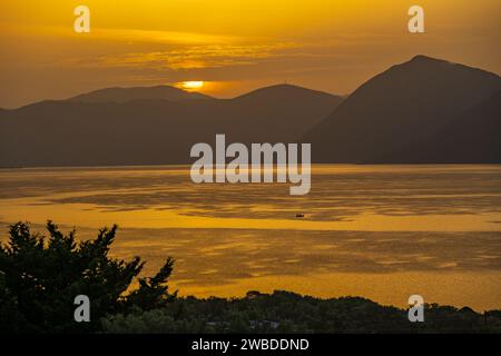 Sonnenaufgang hinter den Bergen des griechischen Festlandes von der Insel Meganisi im Ionischen Meer Stockfoto