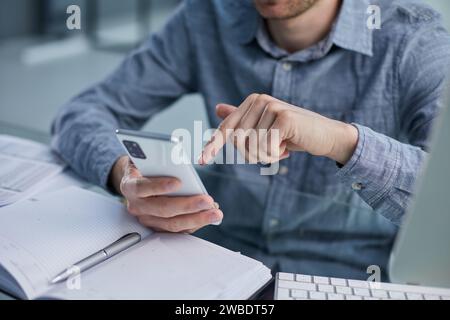 Professioneller Geschäftsmann, der mit einem Smartphone am Schreibtisch arbeitet. Stockfoto
