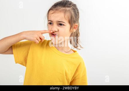 Das kleine Schulmädchen fühlt sich schlecht und riecht nicht, isoliert auf weißem Hintergrund. Stockfoto