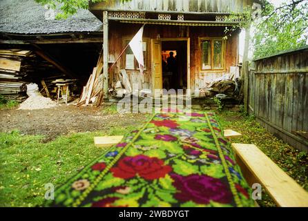 Vrancea County, Rumänien, ca. 1999. Ein gewebter, traditioneller handgefertigter Teppich, der auf einem Tisch im Hof zum Trocknen nach dem Waschen aufgetragen wird. Stockfoto