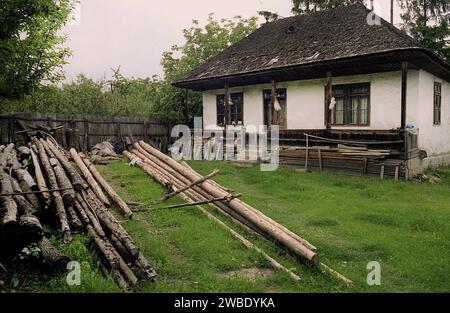 Vrancea County, Rumänien, ca. 1995. Ein traditionelles Haus mit Holzdach in schlechtem Zustand. Holz im Hof gestapelt. Stockfoto