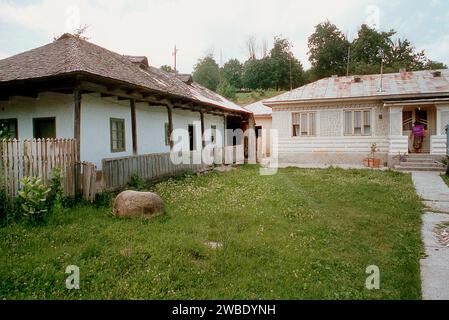 Vrancea County, Rumänien, ca. 1991. Ein Gehöft mit einem alten einfachen traditionellen Haus auf der linken Seite (wahrscheinlich Ende des 19. Jahrhunderts) und einem neueren (wahrscheinlich Mitte des 20. Jahrhunderts), das davor zu sehen ist. Stockfoto